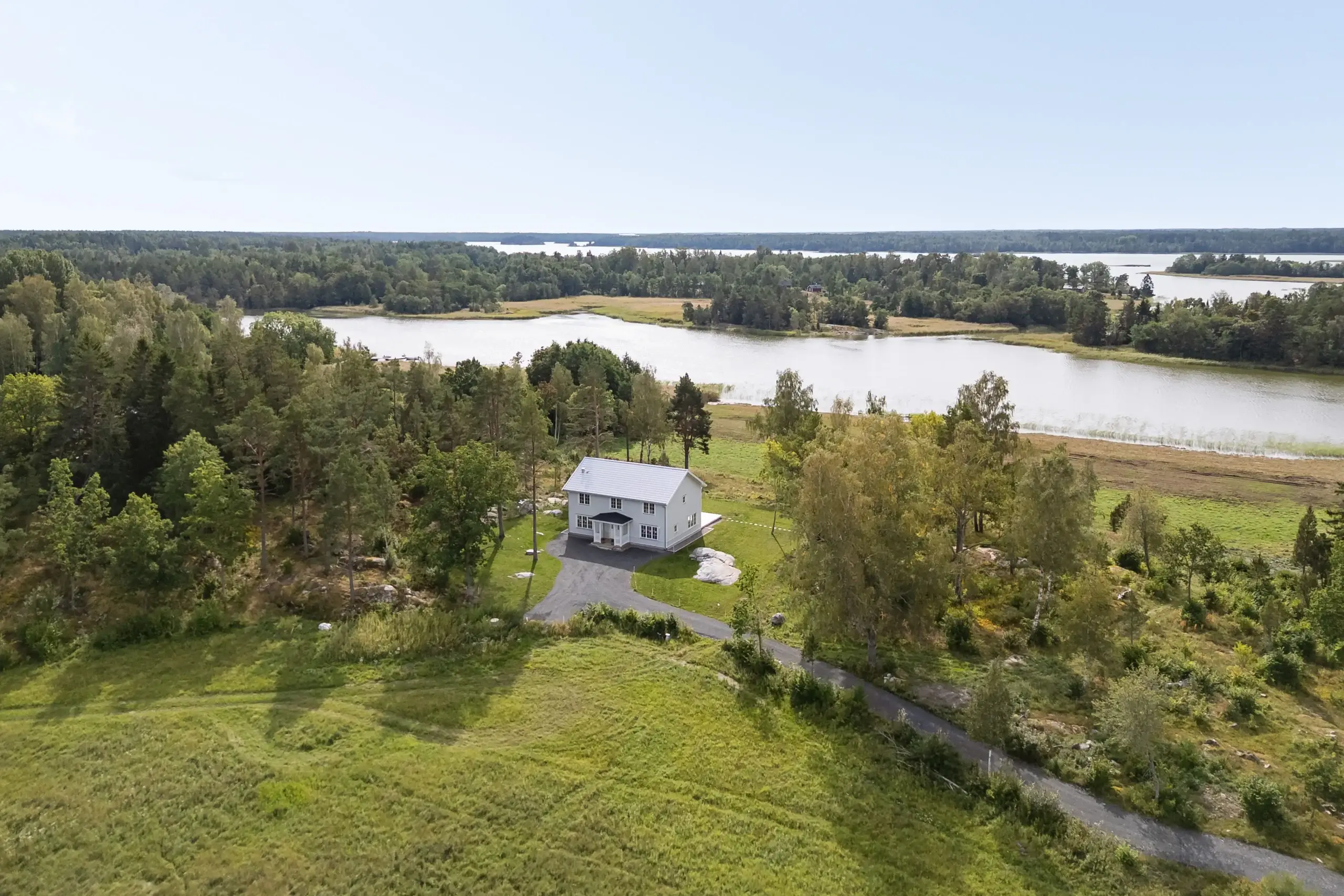 Flygbild över den nyproducerade villan Tuskö 131 med sjöutsikt, till salu i Östhammars skärgård.